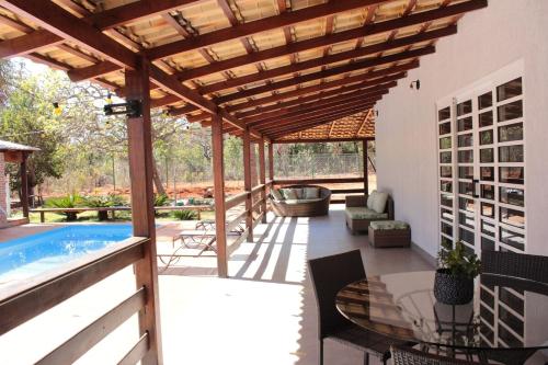 a patio with a swimming pool and a wooden pergola at Casa na fazenda inteira ou quartos individuais no Hostel Recanto da Felicidade Paraopeba in Paraopeba