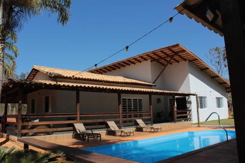 a house with a swimming pool in front of it at Casa na fazenda inteira ou quartos individuais no Hostel Recanto da Felicidade Paraopeba in Paraopeba