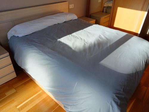 a large white bed in a room with a wooden floor at Apartamento en Puerto de Vega in Navia