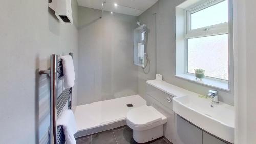 a white bathroom with a toilet and a sink at F49 Junesta, Riviere Towans in Hayle