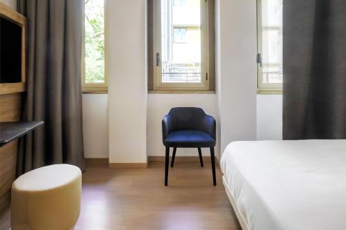 a bedroom with a blue chair and a bed at B&B HOTEL Catania City Center in Catania