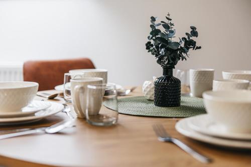 a wooden table with plates and a vase with flowers at Apartmány Petra Voka in Třeboň