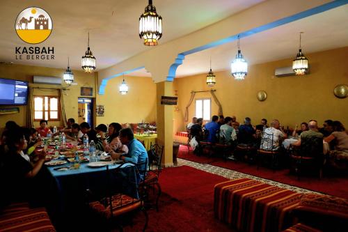 a group of people sitting at tables in a room at Kasbah Du Berger & Piscine in Merzouga