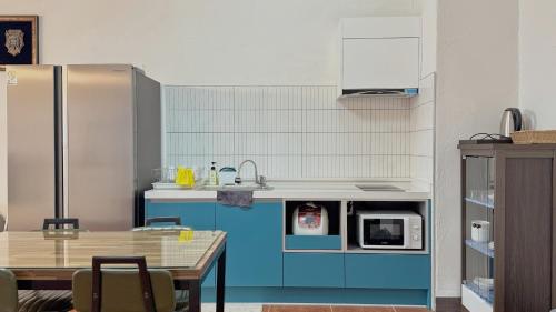 a kitchen with blue cabinets and a table at Sweet Stay Pension in Seogwipo