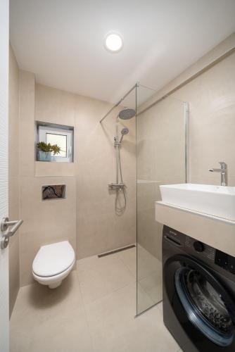 a bathroom with a toilet and a sink and a washing machine at WineAfterSun Chaniotis Beach&Waves steps to beach in Hanioti