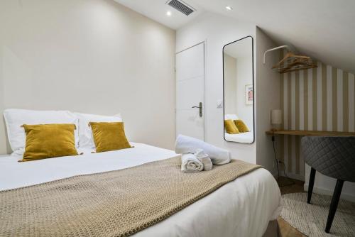 - une chambre avec un lit doté d'oreillers jaunes et d'un miroir dans l'établissement Appartement Cosy & Equipé - 5 - Mon Groom, à Troyes