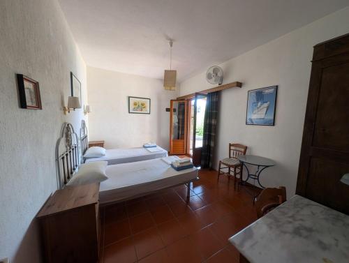 a bedroom with two beds and a table in it at VILLA DOLPHIN VOTSI in Votsi