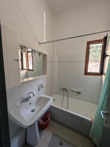 a white bathroom with a sink and a bath tub at VILLA DOLPHIN VOTSI in Votsi