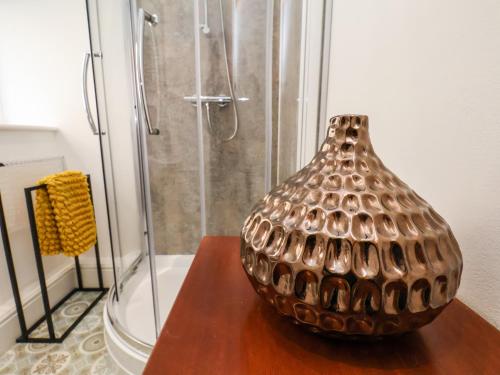 eine Bronzevase auf einem Tisch neben einer Dusche in der Unterkunft The Bungalow in Whitby