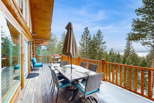 a deck with a table and chairs and an umbrella at Cascade Lakeview Log Cabin in Cascade