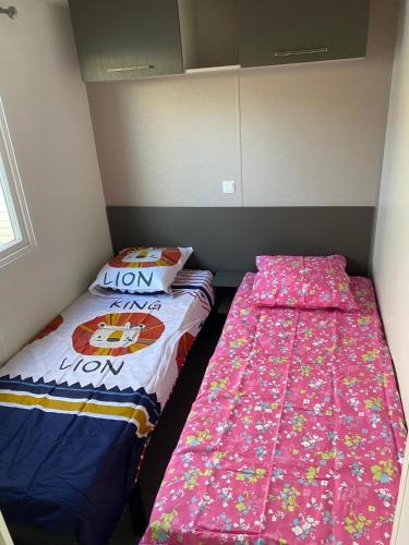 deux lits côte à côte dans une pièce dans l'établissement Mobil Home Dalhias 1, à Valras-Plage