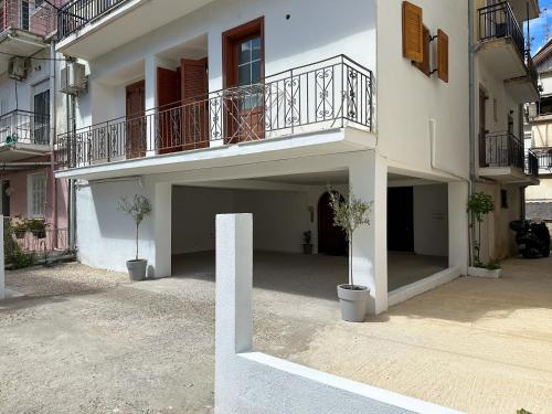 un edificio bianco con balcone e 2 piante in vaso di Lefkada City Escape a Città di Lefkada