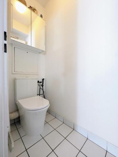 La salle de bains blanche est pourvue de toilettes et d'une armoire. dans l'établissement Chic and comfortable aparts with parking, à Asnières-sur-Seine