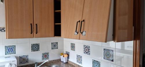 a kitchen with wooden cabinets and tiles on the wall at La casa de Martin in Marchena