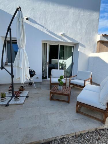 a patio with white furniture and an umbrella at L'angolo di Jana in Porto Pollo