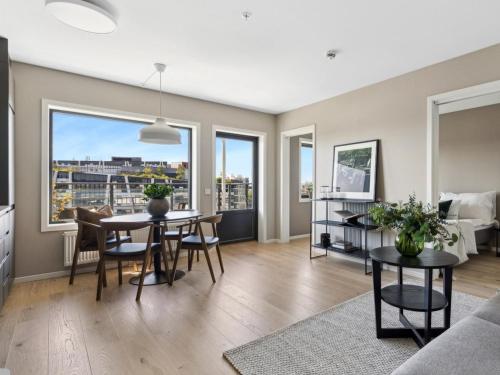 a living room with a table and chairs and a couch at Top modern, big balcony, fully equipped, free parking, in family friendly area in Oslo