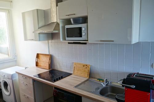 une cuisine avec un évier et un micro-ondes dans l'établissement Appartement bord de vilaine, proche centre et gare, à Redon