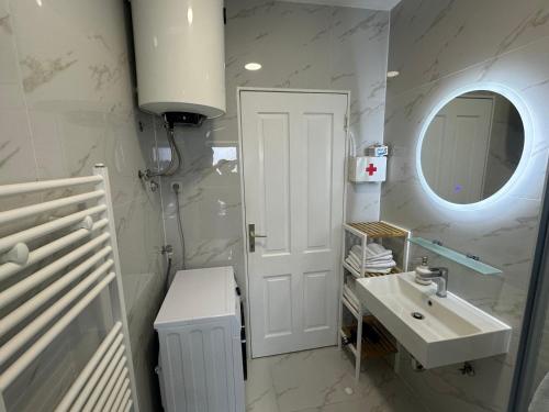 a white bathroom with a sink and a mirror at Apartments Charming in Zadar