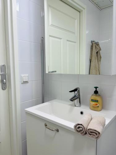a white bathroom with a sink and a mirror at Foliate Living Taimi in Jyväskylä