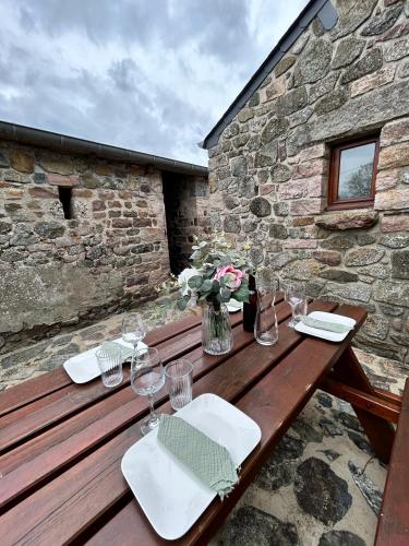 - une table en bois avec des verres à vin et des fleurs dans l'établissement La maison de l'houblonnier vue mer, à Plurien