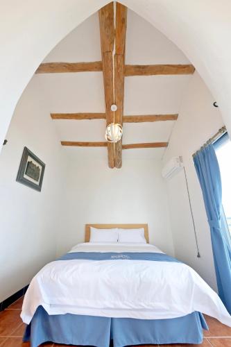 a bedroom with a bed with a blue curtain at Sweet Stay Pension in Seogwipo