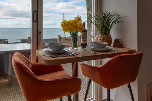 a table with two chairs and a view of the ocean at Bermo Cwtch in Barmouth