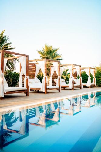 a row of white chairs next to a pool at Mandalin Glamping in Selcuk