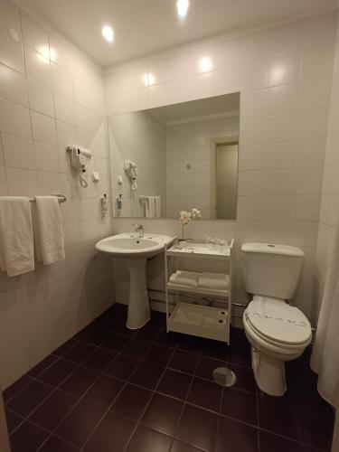 a white bathroom with a toilet and a sink at Vilar Oporto Hotel in Porto