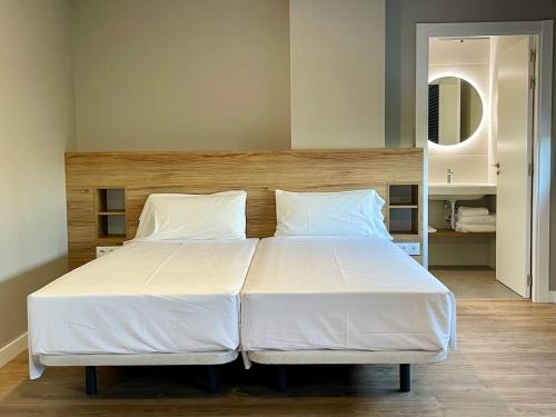 a large bed with white sheets and pillows in a bedroom at Apartamentos CRUNIA - Estudios in A Coruña