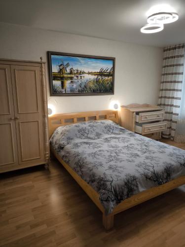 a bedroom with a bed and a painting on the wall at Debreceno apartamentai in Klaipėda