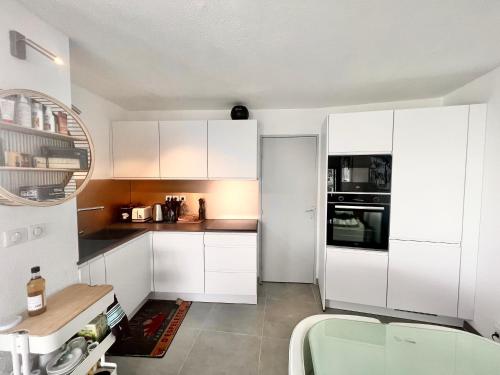 une cuisine avec des armoires blanches et une table à l'intérieur dans l'établissement Superbe Terrasse ROOFTOP Vue Mer, à La Grande Motte