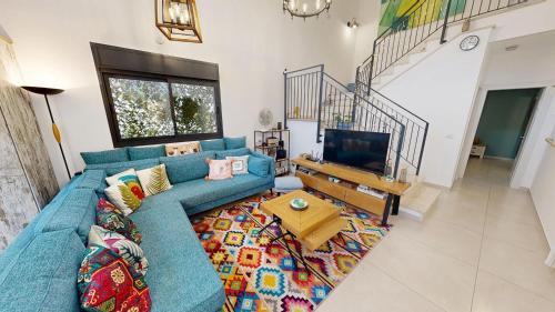 a living room with a blue couch and a television at The Galilee Flame duplex in Shlomi