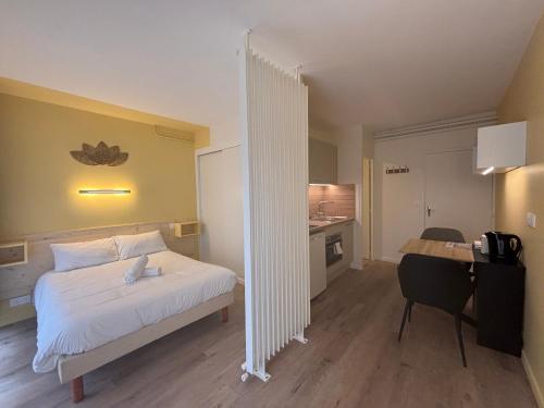 une chambre d'hôtel avec un lit, un bureau et une cuisine dans l'établissement Le D'Artagnan - App 5 - Rez-de-chaussée, à Cazaubon