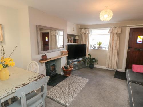 a living room with a fireplace and a television at Wren's Nest in Thirsk