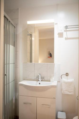 a white bathroom with a sink and a mirror at Spacious studio located in the pedestrian zone in Nicosia