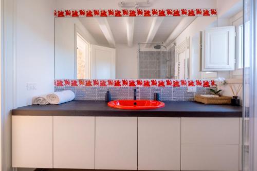 a bathroom with a red sink and a mirror at Villa Santa Margherita in Chiaramonte Gulfi