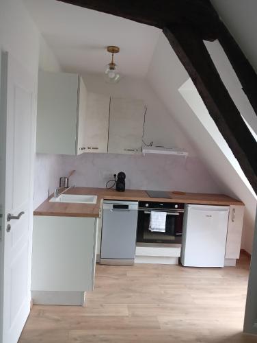 - une cuisine mansardée avec des armoires et des appareils blancs dans l'établissement Maison partagée - Studio haut, à Beauvais