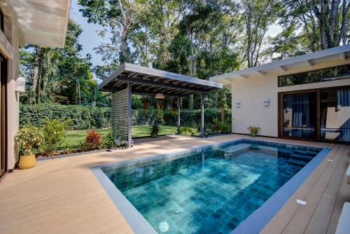 an outdoor swimming pool with a pergola next to a house at Villas Roca del Caribe in Puerto Viejo