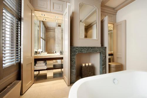 a bedroom with a fireplace and a bathroom with a sink at The Dylan Amsterdam - The Leading Hotels of the World in Amsterdam