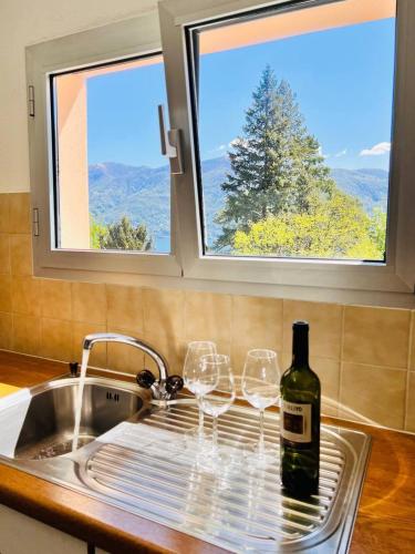 a bottle of wine sitting on a sink with two wine glasses at Sunny modern Apartment Lake View Relax in Brissago