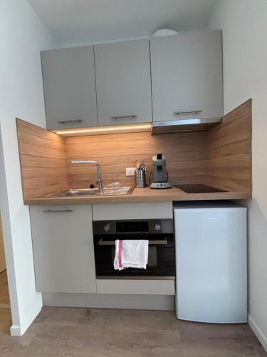 une cuisine avec des armoires blanches et un évier dans l'établissement Le D'Artagnan - App 6 - Ensoleillé, à Cazaubon