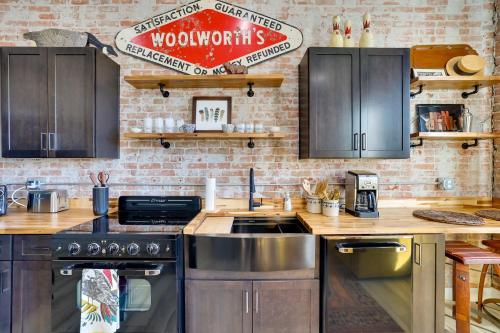 a kitchen with wooden cabinets and a brick wall at Walk to Shops and Eats Charming Dtwn Emmett Apt! in Emmett