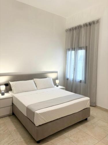a white bedroom with a large bed and a window at Appartamenti le Conchiglie 1 by Ferrocino Holiday in Lido Conchiglie