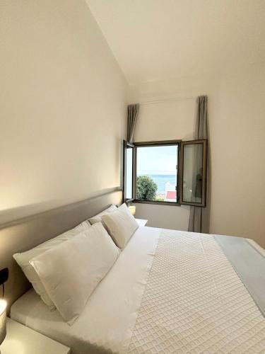 a bedroom with a white bed with a window at Appartamenti le Conchiglie 1 by Ferrocino Holiday in Lido Conchiglie