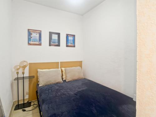 ein Schlafzimmer mit einem Bett mit blauen Laken und Bildern an der Wand in der Unterkunft Carnon vue Port in Mauguio