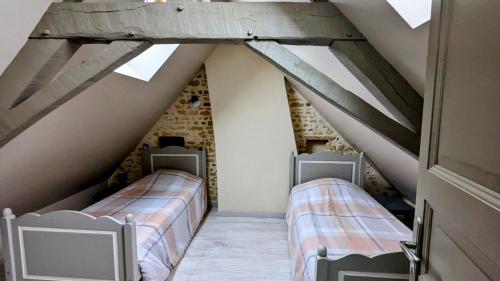 two beds in a attic room with wooden ceilings at À la campagne proche du Mans in Louplande