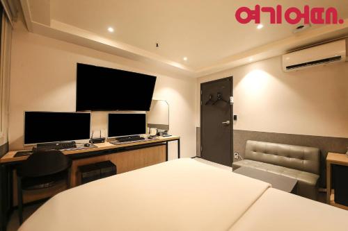 a room with a bed and a desk with two monitors at No25 Hotel Ansan in Ansan