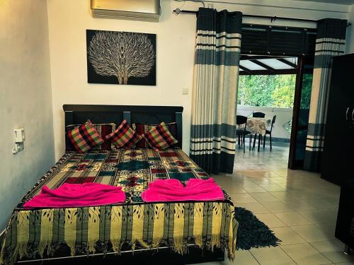 a bedroom with a large bed with pink sheets at Sisila Inn & Restaurant in Warakapola