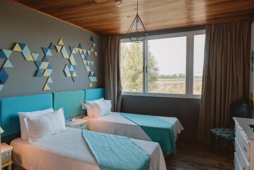 a bedroom with two beds and a window at Puerto Dijama Hotel Boutique in Carmelo