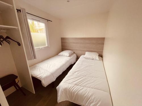 deux lits dans une petite pièce avec une fenêtre dans l'établissement Mobil Home Oliviers 2, à Valras-Plage